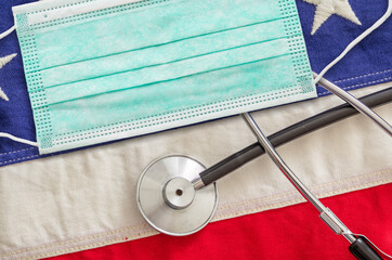 Protective face mask and medical stethoscope on US of America flag background. Coronavirus concept