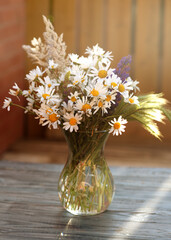 Some wildflowers in a vase on wooden background 