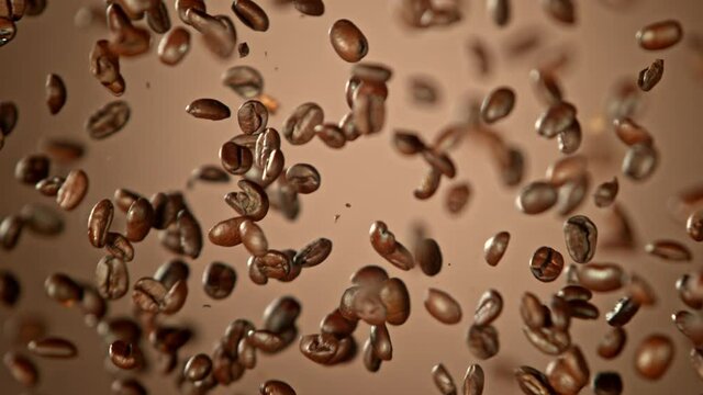 Super Slow Motion Shot of Crashing Coffee Beans on Brown Gradient Background at 1000fps.