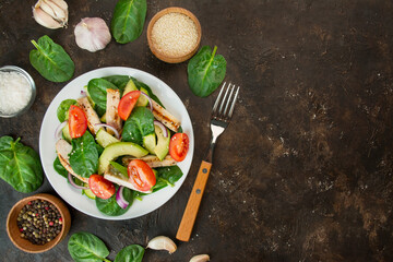 A healthy salad of chicken breast, fresh vegetables, spinach leaves, avocado and tomatoes on a dark background. Salad of greens with meat. The concept of diet food. Copy space. Benner food.