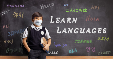 Schoolboy with a protective mask in front of a blackboard with text learn languages