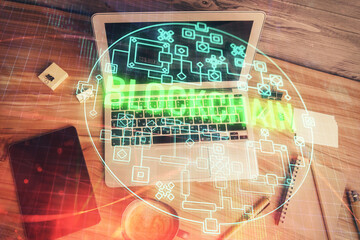 Blockchain theme hologram drawings over computer on the desktop background. Top view. Multi exposure. Concept of cryptoeconomy.