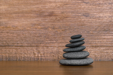 Obraz na płótnie Canvas Stack of black spa stones on wooden background. Simplicity rock zen sculpture