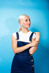 young pretty teenage modern hipster girl posing emotional happy on blue background, lifestyle people concept