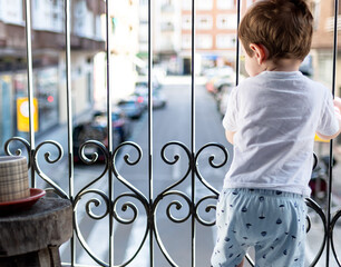 Child looking out of the balcony in the quarantine.