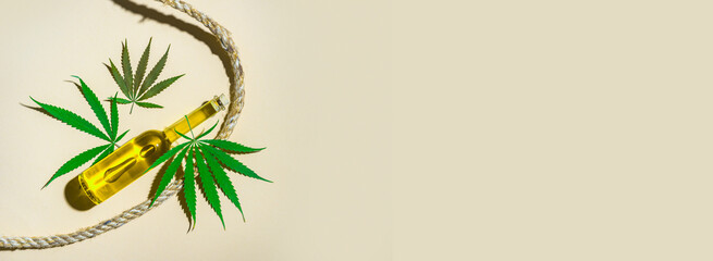 Naklejka premium Bottles with CBD oil, medical marijuana leaf and hemp rope on camel color background. Natural product concept.