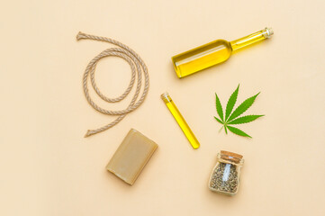 CBD oil, cannabis leaf, hemp rope and seeds on camel color background. The concept of a natural and organic product. Medical marijuana cbd oil.