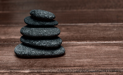 Stack of black spa stones on wooden background. Simplicity rock zen sculpture. Vintage color filter