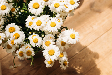 bouquet of white field daisies in a vase on the brown wooden floor