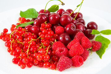 Assorted red fresh berries on a plate on a white background.