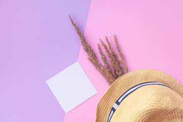 Light straw hat and wildflowers on a pink background. summer concept.