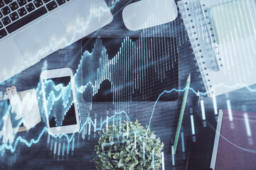 Double exposure of forex chart hologram over desktop with phone. Top view. Mobile trade platform concept.