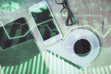 Double exposure of forex chart hologram over desktop with phone. Top view. Mobile trade platform concept.