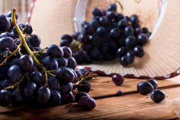 Bunches of fresh ripe red grapes on the surface with a wooden texture. Beautiful background with a...