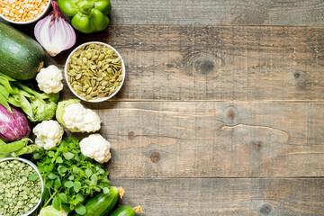 Top view set raw of green and purple vegetables and protein for vegetarians spread on dark wooden background. Copy space.