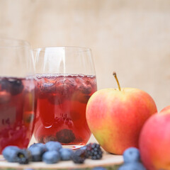 delicious red  berries Cocktail with blueberries in front of a blurred brown background