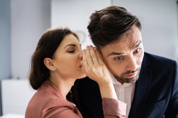 Woman Whispering Gossip In Friend's Ear At Workplace