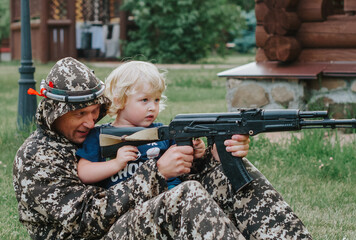 father and son in camouflage ready to play in laser tag shooting game with a weapon outdoor