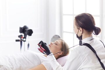 Young woman undergoing procedure of eyebrow permanent makeup in beauty salon