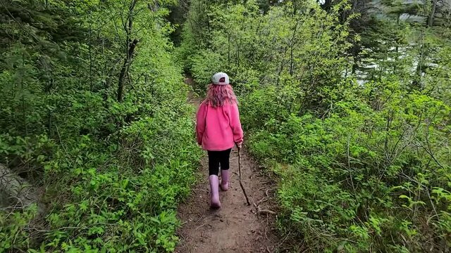 Little girl in pink hiking a forest path