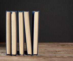stack of various hardback books on the background of an empty black chalk board