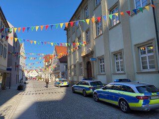 Bunte Wimpel hängen über der Straße, Pflasterstein, alte Häuser, Polizeiautos parken am...