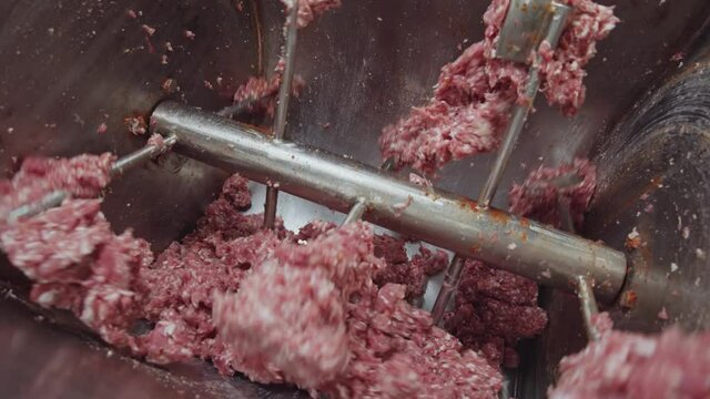 Meat grinder. Close-up industrial cutting mixer grinding minced meat. Factory for production of meat delicacies and sausages. Manufacturing. Slow motion. Cooking process.