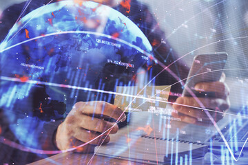 Double exposure of man's hands holding and using a phone and financial graph drawing. Analysis concept.