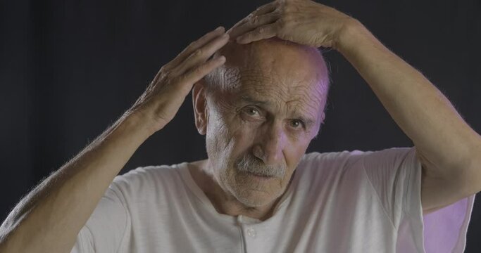 An old bald man is controlling his hair. Balding, lose hair concept.