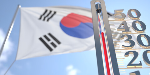 Thermometer shows high air temperature against blurred flag of South Korea. Hot weather forecast related 3D rendering