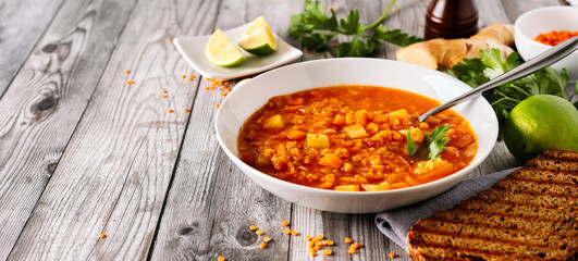 Side view of a plate with winter lentil soup on gray rustic background
