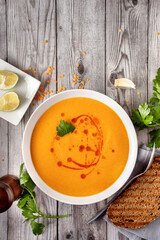 Top view of a plate with creamy winter lentil soup of orange color