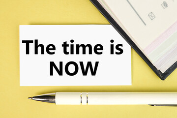 the time is now. text on white paper. on a yellow background with a pen