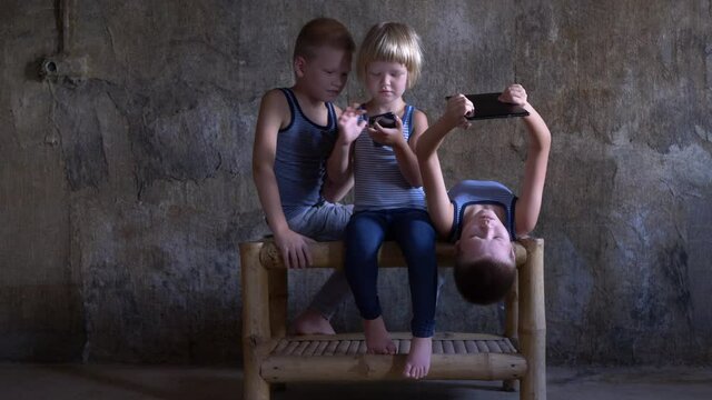 Funny boys play with smartphones and tablet in studio sitting on bamboo table