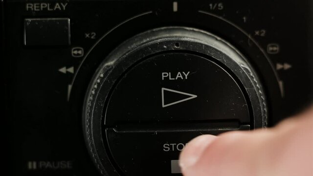 male hand presses play and then stop. A man rewinds a cassette on an old VCR.