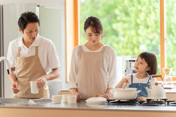 キッチンで料理を作る女の子と両親