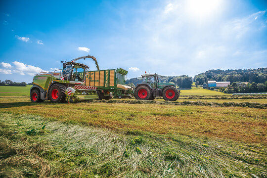 BAVARIA / GERMANY - AUGUST 07,2020: Claas harvester and a Fendt 926 with a Krone ZX400GL trailer works on a field.