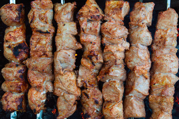 pork kebab on skewers is grilled over charcoal, smoke over a barbecue, the last degree of cooking, close