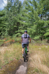 Obraz na płótnie Canvas Man riding a mountain bike through the forest at Torrance Barrens in Muskoka