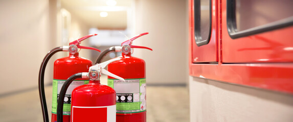 Close-up the red fire extinguishers tank at the exit door in the building concepts for emergency safety fire prevention rescue and fire services.