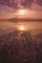 朝陽の昇る空を湖面に映す湖。屈斜路湖、北海道、日本。