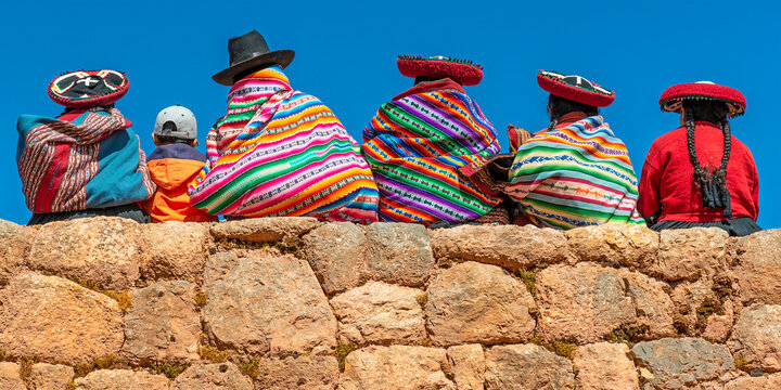 Peruvian Quechua indigenous people in traditional clothing on an Inca wall in Chinchero, Cusco, Peru.