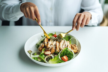 Closeup image of a woman eating chicken salad on table in the restaurant