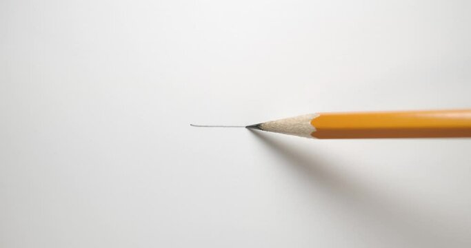 Drawing a straight line across paper with a yellow pencil.
