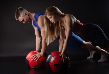 a guy and a girl train with a heavy stuffed ball