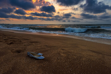 Fototapeta na wymiar Lost women shoes on sea shore