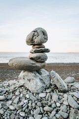 The figure of stones standing on each other, on the beach against the sea.