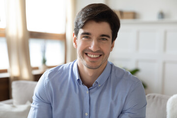 Profile picture of young handsome man sitting on sofa, enjoying talking with friends in social...