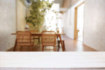 Empty wooden desk space and blurry background of home window for product display montage.