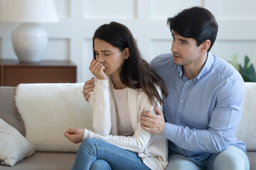 Affectionate caring young man embracing stressed young woman, overcoming problem together. Loving...